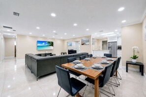 A modern dining area with a wooden table set for six, surrounded by black chairs.