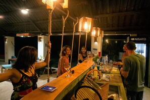 Una zona de bar con mostrador de madera, luces colgantes y dispensador de agua.
