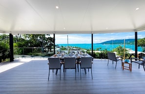 An outdoor dining area with a table set for four, overlooking a scenic coastal view.