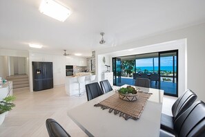 Una cocina moderna con refrigerador integrado y comedor con vista al océano.