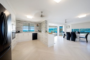 A modern kitchen with a large island, built-in appliances, and a view to the outside. - Airlie Blue On Blue (Airlie Beach)