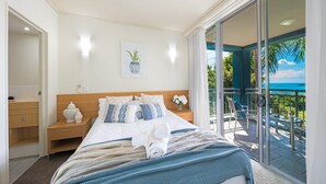 Una camera d'albergo con un letto, un comodino, una finestra vista all'esterno e un balcone con sedie.