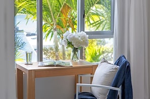 Ein Holztisch mit einer Vase weißer Blumen, einem Glas Wasser und einem offenen Buch.