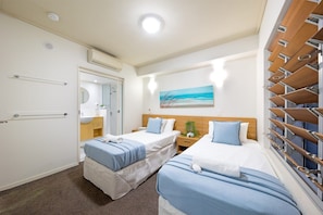 Ein Hotelzimmer mit zwei Betten, einem Badezimmer und Meerblick.