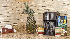 A kitchen with a bamboo-patterned backsplash, a pineapple, a coffee maker, and a bag of coffee. - Cococabana4 newly renovated 1BR/1BA apar in downtown Coco, 5 min walk to beach. (Playas del Coco)