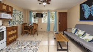 A compact living space with a kitchenette, dining area, and a sofa with floral cushions. - Cococabana4 newly renovated 1BR/1BA apar in downtown Coco, 5 min walk to beach. (Playas del Coco)