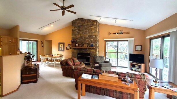 A spacious living area with a fireplace, a dining table, and a kitchen area with wooden cabinets and a refrigerator. - On the Island!  Three bedroom, two bath home. (Holiday Island)