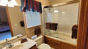 A bathroom with a glass-enclosed shower, a toilet, a sink, and a mirror. - On the Island!  Three bedroom, two bath home. (Holiday Island)