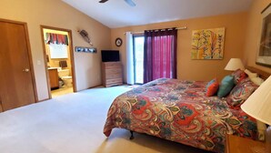 A bedroom with a large bed, a dresser, a window with curtains, and a painting on the wall. - On the Island!  Three bedroom, two bath home. (Holiday Island)