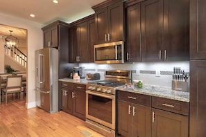 A modern kitchen with dark wood cabinets, stainless steel appliances, and a granite countertop.