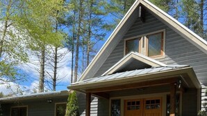 A two-story house with a porch, wooden deck, and potted plants. - Casa Cortina: Eclectic Highlands Retreat w/ Covered Deck | 4 Min to Main Street (Highlands)