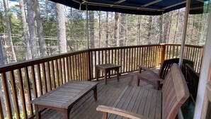 A wooden deck with a bench and a table, surrounded by a railing, overlooking a forested area. - Casa Cortina: Eclectic Highlands Retreat w/ Covered Deck | 4 Min to Main Street (Highlands)