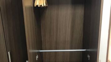 A dark wooden wardrobe with a metal rod and wooden hangers.