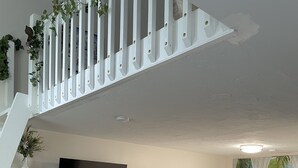 A bedroom with a bed, a desk, a chair, a dresser, a TV, and a staircase.