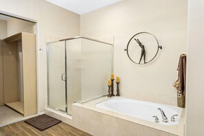 Ein modernes Badezimmer mit einer Duschkabine aus Glas, einer freistehenden Badewanne und einem an der Wand befestigten Spiegel.