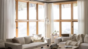 A modern living room with a sofa, coffee table, and a view through large windows. - Outpost: Moose Creek 25 - Private Hot Tub! (Teton Village)