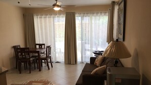 Ein Wohnzimmer mit einer Couch, einem Esstisch mit Stühlen, einem Deckenventilator und einer Lampe.