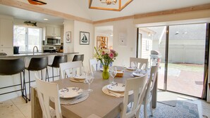 Een eethoek met een tafel voor vier personen, een keuken op de achtergrond en een schuifdeur naar een achtertuin.