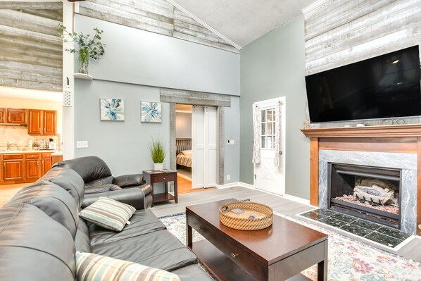 A living room with a fireplace, a sofa, a coffee table, and a television. - Indian Lake Escape for Fall Fishing & Biking (Huntsville)