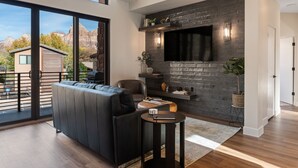 Ein modernes Wohnzimmer mit großem Fenster, Kamin, Fernseher und einer Sitzecke.