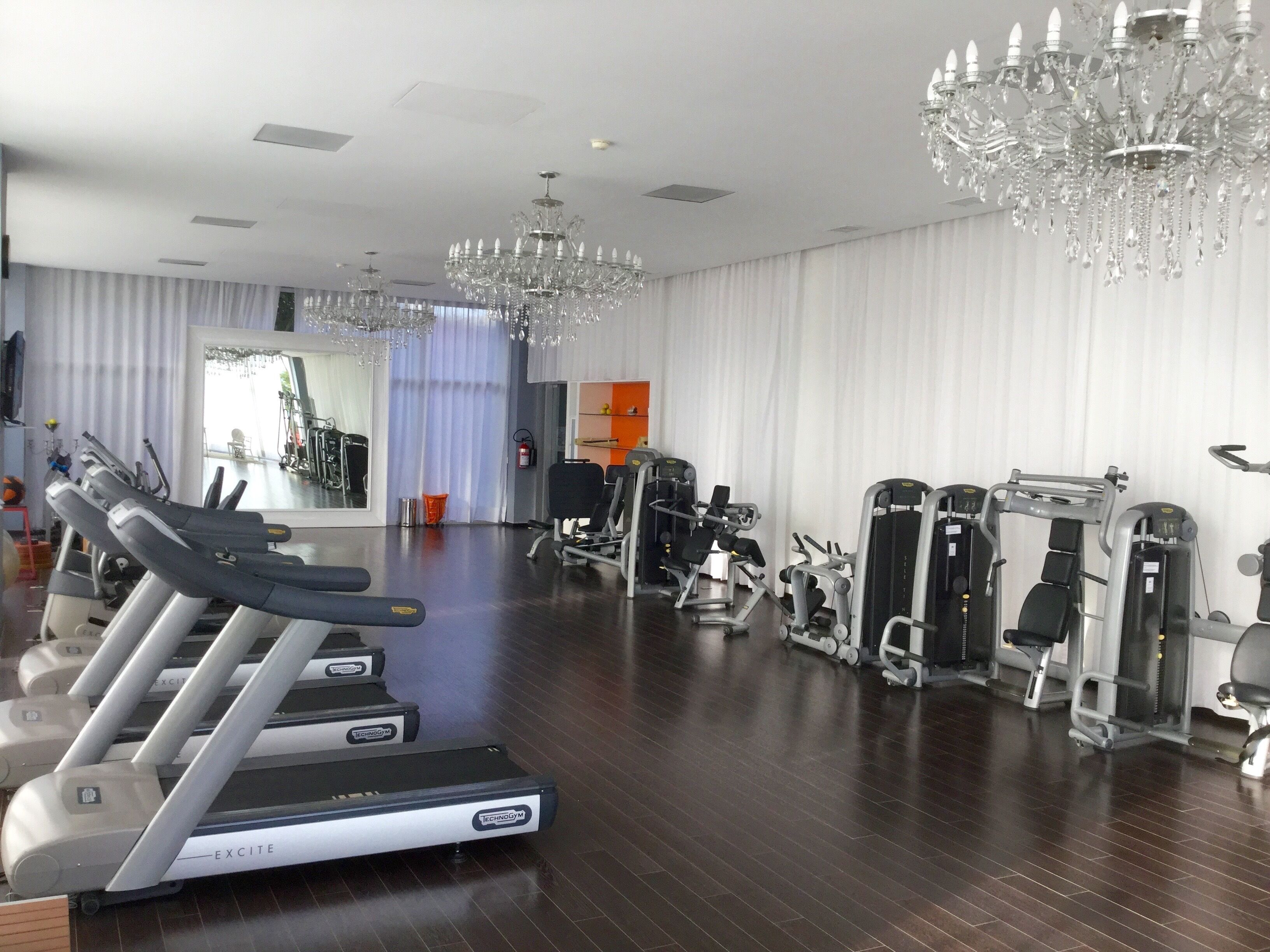 Ein Fitnessstudio mit Laufbändern, Kraftgeräten und einem großen Spiegel.