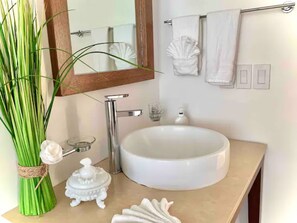 Un baño con lavamanos blanco, un espejo y un perchero para toallas.