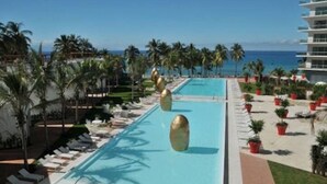 A pool area with lounge chairs and palm trees, overlooking the ocean. - Icon Vallarta Apartments (Puerto Vallarta)