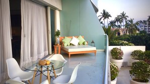A balcony with a bed, a glass table, and chairs. - Icon Vallarta Apartments (Puerto Vallarta)