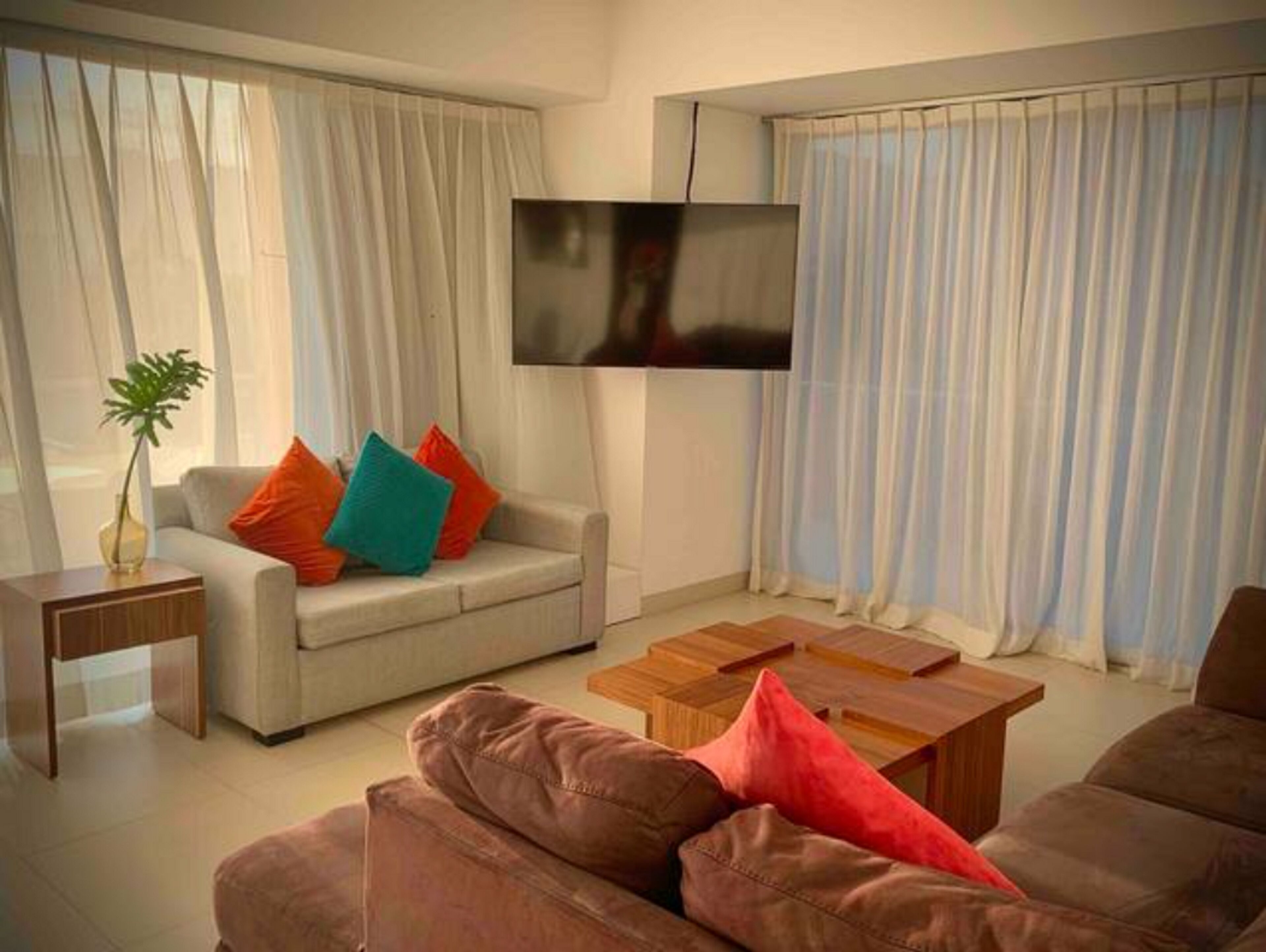 A modern living room with a sofa, a coffee table, and a TV mounted on the wall.