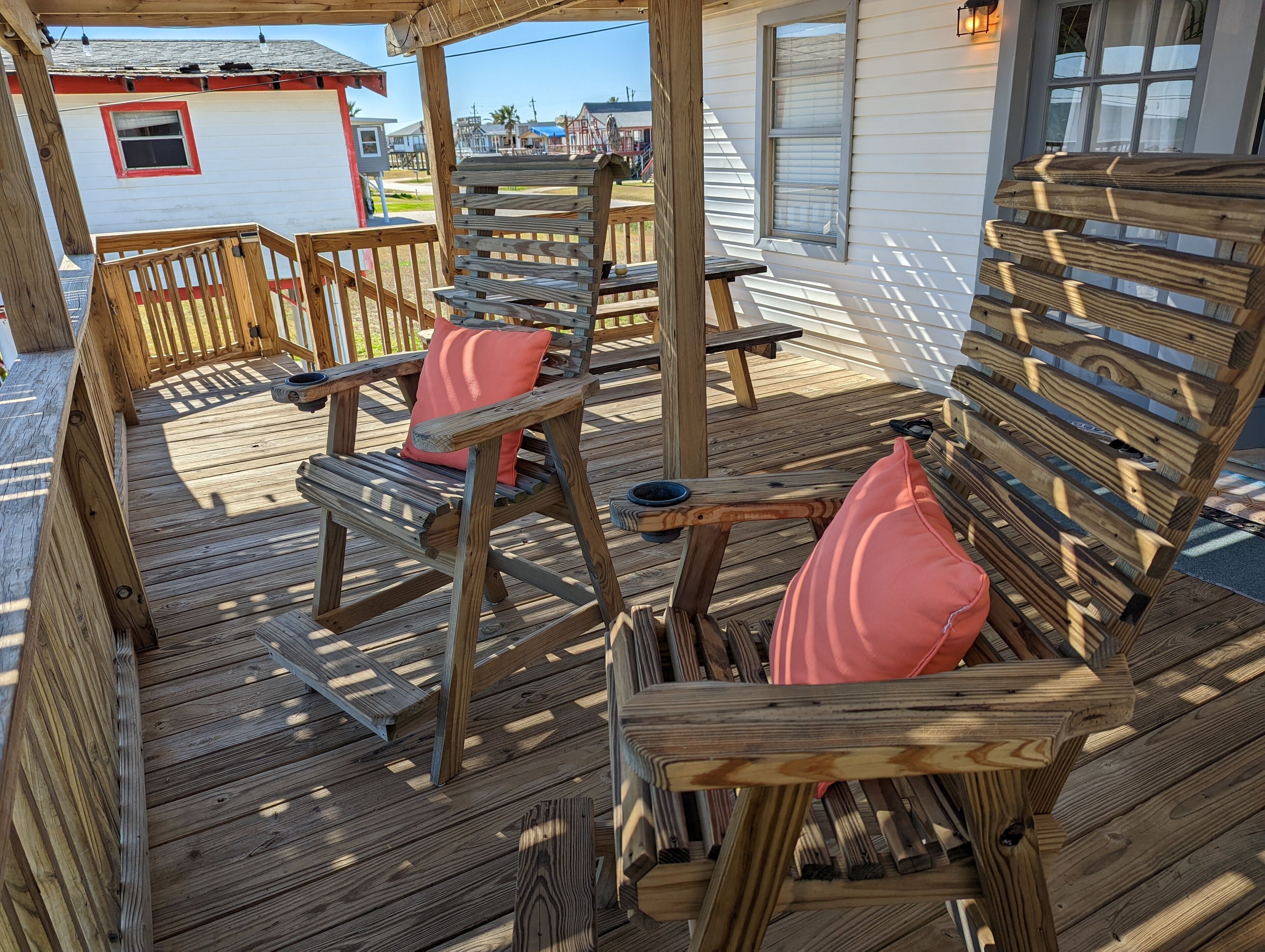A wooden deck with outdoor seating, including chairs and a table.