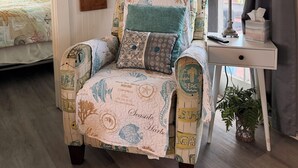 Ein Sessel mit Strandmotiv, ein Nachttisch mit Lampe und ein Wandschild mit der Aufschrift 'Beach House'.