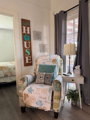 A chair with a beach-themed cover, a bedside table with a lamp, and a wall sign that reads 'Beach House.' - Charming recently updated beach house with ocean views  (Freeport)