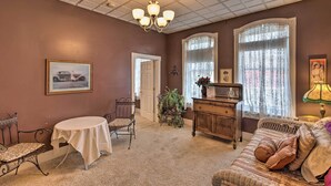 A room with a chandelier, a dining table with chairs, a sofa, a dresser, and a window with lace curtains. - Pet-Friendly Apt: 2 Blocks to Riverside Park! (Yankton)