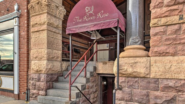 A stone building with a red awning labeled "The River Rose."