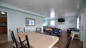 A spacious living area with a dining table, chairs, a sofa, and a TV. - Fins Up Unit #1 - On The Bayside - Downtown - Spacious Unit! (Ocean City)