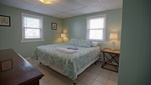 A bedroom with a bed, two bedside lamps, a small table, and a window. - Fins Up Unit #1 - On The Bayside - Downtown - Spacious Unit! (Ocean City)
