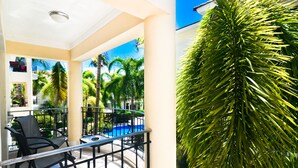 Ein Balkon mit Pool, Palmen und einem Stuhl.