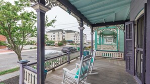 Eine Veranda mit Holzbalkon, einer Bank und einem überdachten Bereich mit Verzierungen.
