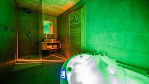 Une salle de bain moderne avec une douche à parois de verre, un meuble-lavabo en bois et une grande baignoire.