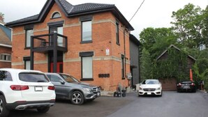 A two-story brick building with a black roof, numbered 2148. There are cars parked in front, and a garage door is visible.