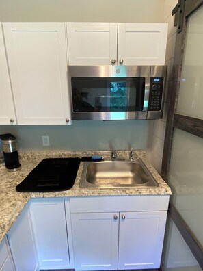 Functional kitchen with a sink, microwave, and kettle.