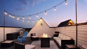 Um terraço no telhado com móveis de exterior, lareira e luzes de corda.