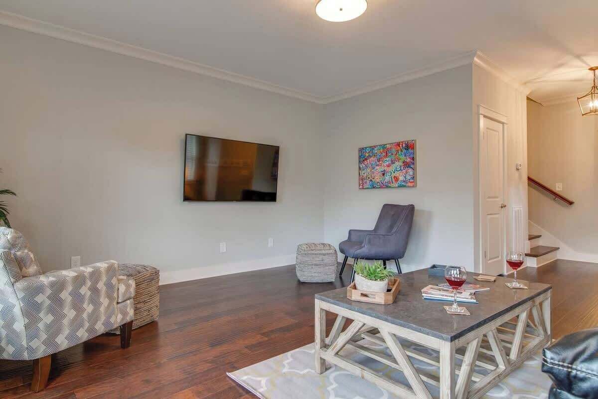 A living room with a sofa, a chair, a coffee table, and a TV mounted on the wall.