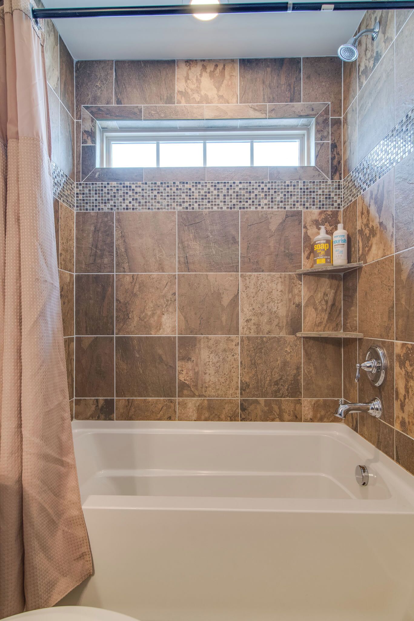 Een badkamer met een bad, een douche en een raam boven de douche.