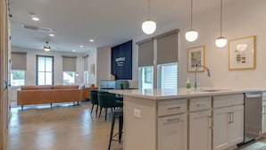 A modern kitchen with a central island, white cabinetry, and pendant lighting.