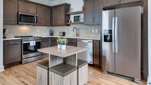 A modern kitchen with dark wood cabinets, stainless steel appliances, and a central island with seating.