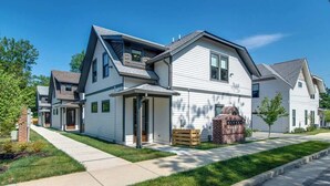 A modern two-story house with a front porch, a brick fireplace, and a well-maintained lawn.