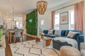 Un salon moderne avec un canapé bleu, une table basse en bois et un mur vert.