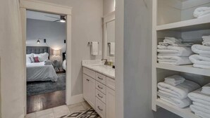 Un baño de hotel con un espejo grande, armarios blancos y una repisa con toallas dobladas.