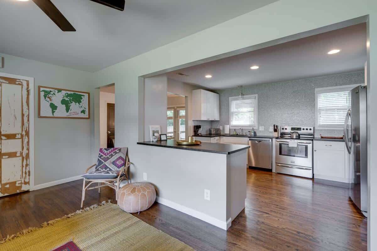 A modern kitchen with a central island, stainless steel appliances, and a view into the dining area.